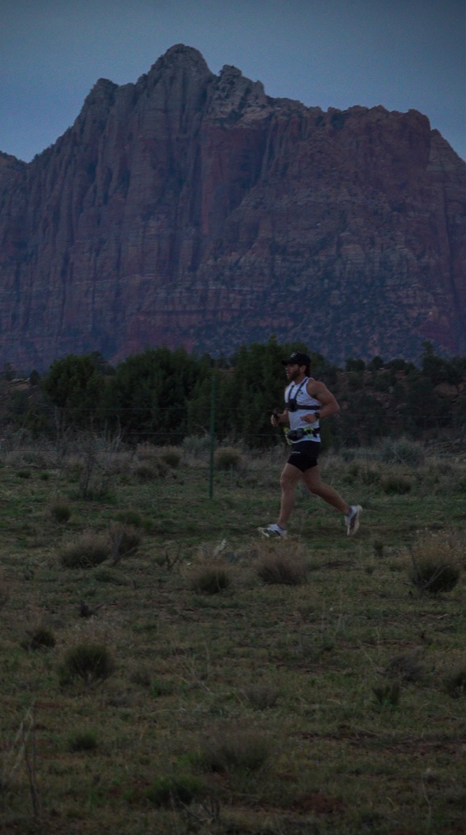 Trevor running with Zion's red walls towering behind him