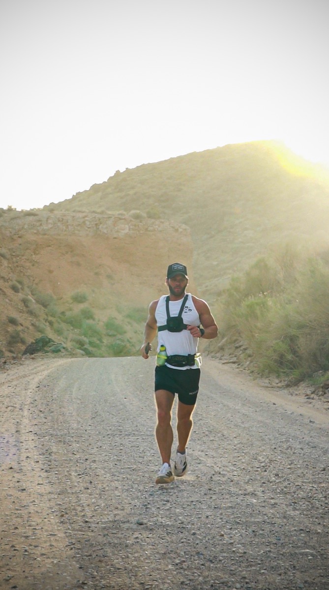 Trevor on the gravel road, sun flare behind the hills